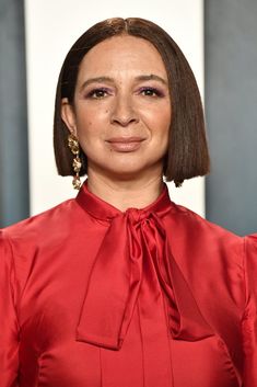 a woman wearing a red blouse and gold earrings