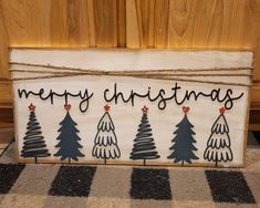 a wooden sign with christmas trees painted on it