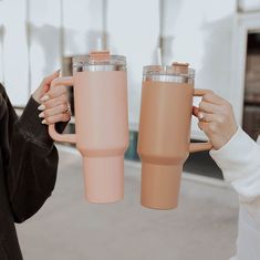 two women holding up coffee mugs in front of each other with their hands on the cups