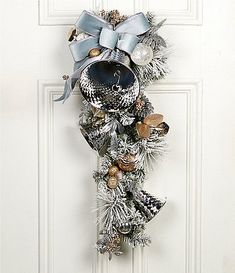 a christmas wreath hanging on the front door decorated with bells and other holiday decorations,