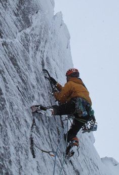 a man climbing up the side of a snow covered mountain