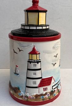 a ceramic container with a lighthouse painted on it