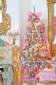 a pink christmas tree in a living room with gold trimmings and ornaments around it