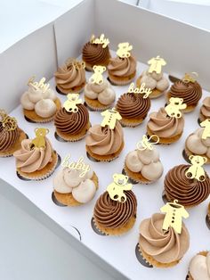 a box filled with lots of cupcakes covered in frosting and gold decorations