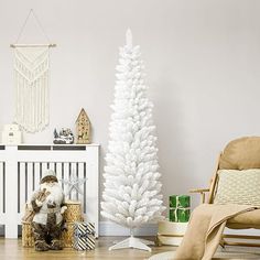 a small white christmas tree in a living room next to a chair and other decorations