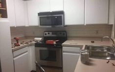 an empty kitchen with stainless steel appliances and white cupboards, including a stove top oven