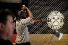 a man hitting a ball with a bat in his hand while another man looks on