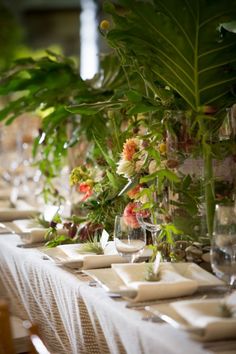 the table is set with place settings and flowers in glass vases on each side