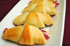 several pastries are arranged on a long white platter with red cloth in the background