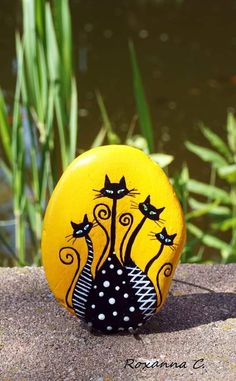 a yellow painted rock with black cats on it