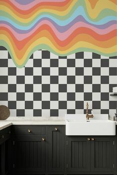 a black and white checkered wall in a kitchen next to a sink with a faucet