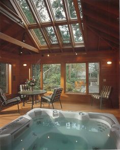 an indoor hot tub in the middle of a wooden floored room with large windows