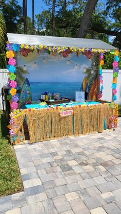 a table with some decorations on it near the ocean and trees in front of a building