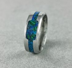 -Mineral(s): Malachite, Blue Achat -Opal(s): Blue Opal -Ring Material: Stainless Steel 316L -Ring Width: 6mm, 8mm -Shipping: EU:6-10 Workdays, Outside The EU: 7- 14 Workdays -Ring Inside: Comfort Fit Introducing our exquisite Handmade Stainless Steel Ring with a captivating inlay filled with crushed blue achat, malachite minerals, and blue opal. This meticulously crafted piece of jewelry is a true testament to the beauty of nature's wonders and the artistry of our skilled artisans. The central feature of this ring is the inlay, carefully filled with crushed blue achat, malachite minerals, and blue opal. Let's delve into the enchanting meanings behind these precious minerals, each adding a touch of mystique to this stunning piece: Blue Achat: Known for its calming and soothing properties, b Engagement Ring Opal, Malachite Ring, Blue Opal Ring, Malachite Rings, Ring Opal, Protection Stones, Ring Blue, Ring Black, Ring Promise