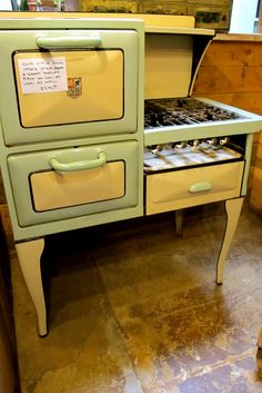 an old fashioned green stove sitting on top of a wooden floor