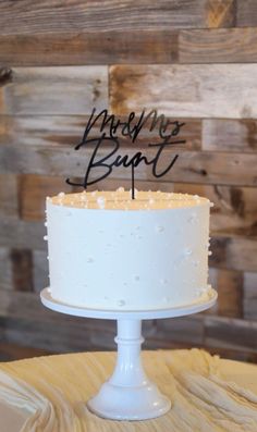 a white cake sitting on top of a table next to a wooden sign that says baby's me, but