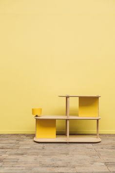 a yellow shelf sitting on top of a wooden floor in front of a yellow wall