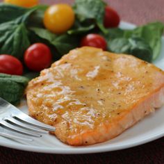 a white plate topped with salmon and spinach next to a pile of cherry tomatoes