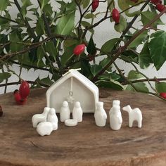 small white figurines sitting on top of a wooden table next to a tree