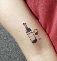 a woman's arm with a bottle of wine and a glass tattoo on it