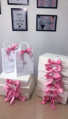 three white boxes with pink bows are sitting on a table next to pictures and frames