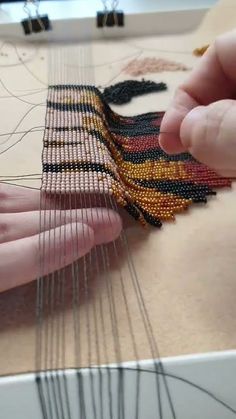 two hands are working on a weaving project