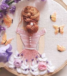 a woman in a pink dress is surrounded by flowers and butterflies on a wooden hoop