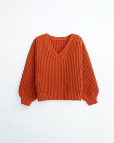 an orange sweater is hanging on the wall, and it's not too warm