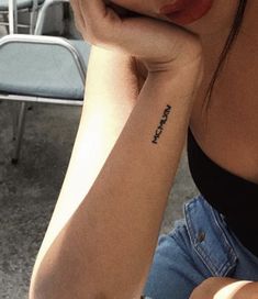 a woman with a small tattoo on her arm sitting in front of a stack of chairs