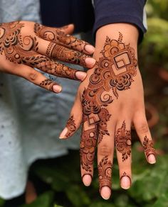 two hands with henna tattoos on them