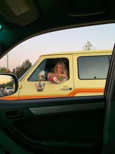 a woman sitting in the driver's seat of a yellow van with an orange and white stripe