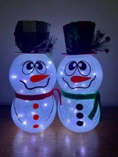 two lighted snowmen with hats and scarfs