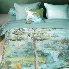 a bed covered in blue and green comforter next to a wicker basket on the floor