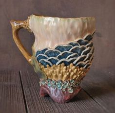 a ceramic cup with blue and white designs on it's sides sitting on a wooden surface