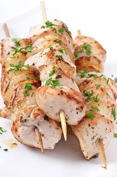 chicken skewers with parsley on a white plate