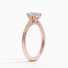 a rose gold engagement ring with three stones on the band and an oval shaped center stone