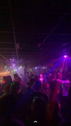 a group of people dancing in a dark room with lights on the ceiling and floor