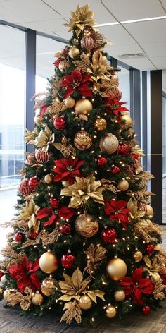 a christmas tree decorated with gold and red ornaments in an office building, looking festive