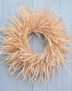 a close up of a dried wreath on a wooden wall with blue boards in the background