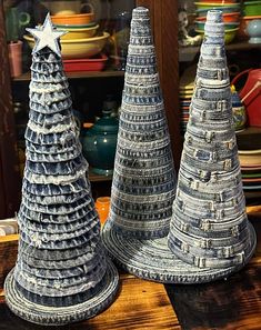 two ceramic christmas trees sitting on top of a wooden table