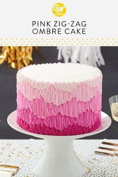 a pink and white ombree cake on a table with gold confetti