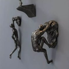 three metal figurines hang on the wall next to each other in different positions