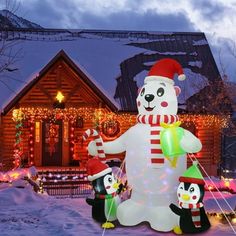 an inflatable snowman with two penguins and a christmas tree