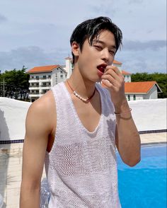 a young man brushing his teeth next to a swimming pool