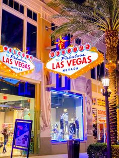 the las vegas sign is lit up at night in front of a building with palm trees