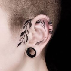 a man with a tattoo on his ear and behind the ear is a black circle