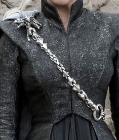 a close up of a person wearing a dress with chains on it's shoulders