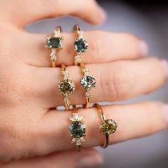 a woman's hand with five different colored diamond rings on her left and right fingers