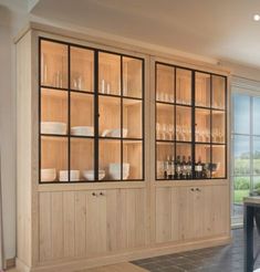 a dining room table and chairs with glass doors on the back wall, in front of a large window