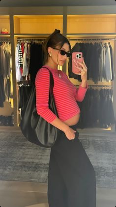 a woman taking a selfie in front of a closet with clothes and handbags